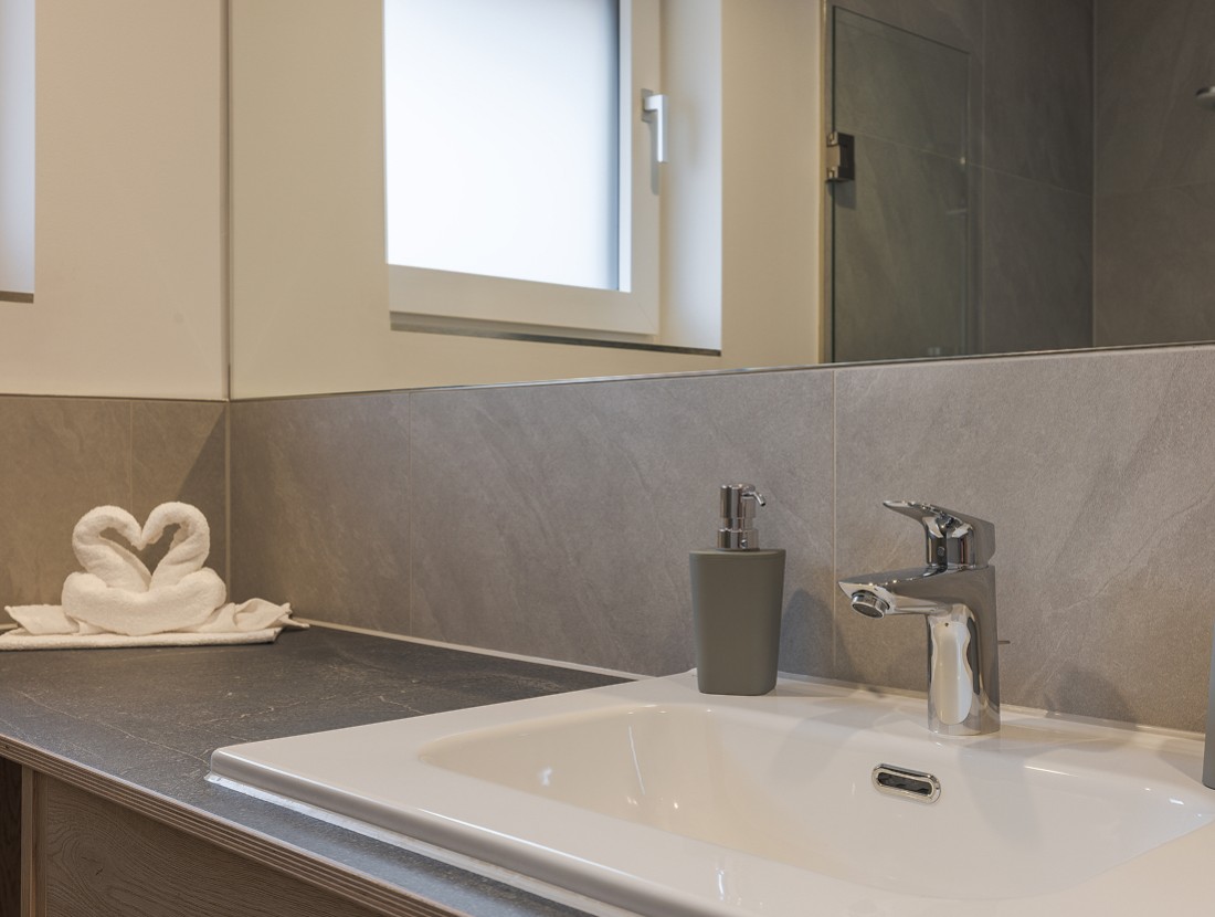 Ein Badezimmer mit einem Waschbecken und gefalteten Handt&uuml;chern in Form von Schw&auml;nen