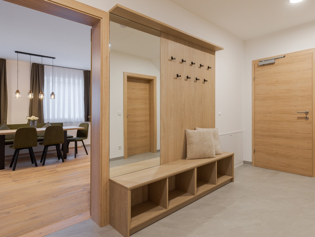 Flur mit Holz-Garderobe und Spiegel, angrenzend Esszimmer mit Tisch und St&uuml;hlen