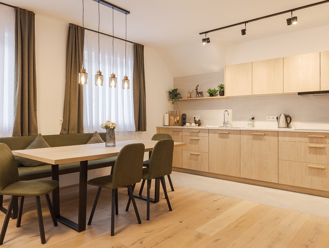 Moderne, helle K&uuml;che mit Holzm&ouml;beln, Esstisch und dekorativen H&auml;ngelampen